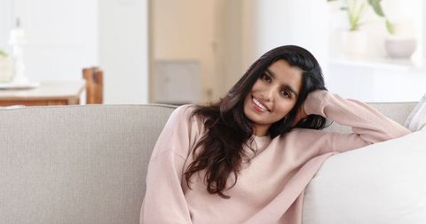 Relaxed Woman in Comfortable Pink Sweater Smiling on Sofa