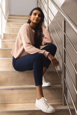 Stylish young woman relaxing on modern staircase in casual wear