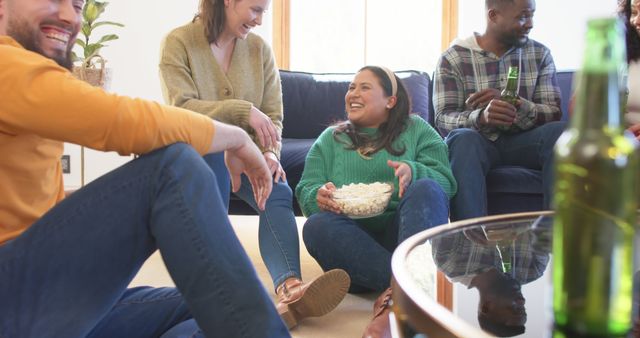 Group of friends enjoying time together at home, sitting on floor and couch, sharing popcorn and drinks. Useful for concepts related to friendship, leisure time, social gatherings, and home lifestyle.