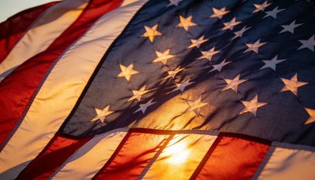 American flag billowing in warm sunset light close-up of stars and stitched stripes
