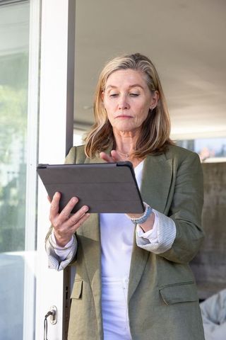 Senior Professional Woman Using Tablet at Office Door