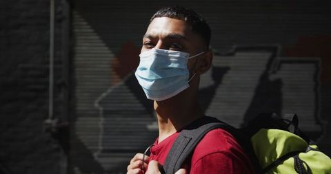 Traveler With Mask Walking Through Urban Environment During COVID-19