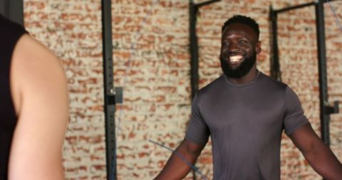 Smiling fitness instructor guiding jumprope workout in gym