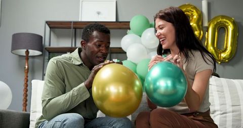 Multiracial Couple Preparing Balloons for Birthday Celebration