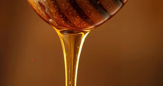 Slow Motion Streaming Honey from Wooden Dipper