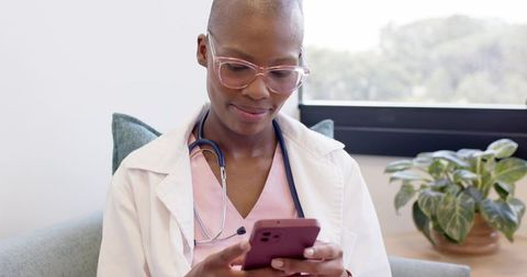 Doctor checking patient notes on smartphone in modern clinic with stethoscope
