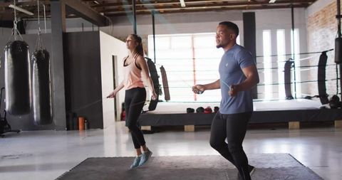 Athletic pair jumping rope in boxing training facility