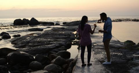 Romantic Evening at Sunset with Couple on Rocky Beach