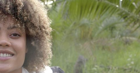 Close-Up of Smiling Woman with Curly Hair in Nature