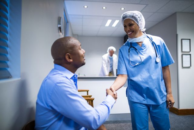 Female doctor in scrubs shaking hands with male patient in hospital setting. Ideal for use in healthcare, medical consultation, patient care, and doctor-patient relationship themes. Can be used in brochures, websites, and advertisements promoting healthcare services and medical professionalism.
