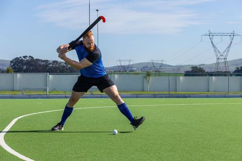 Dynamic Athlete Preparing to Strike on Field Hockey Pitch