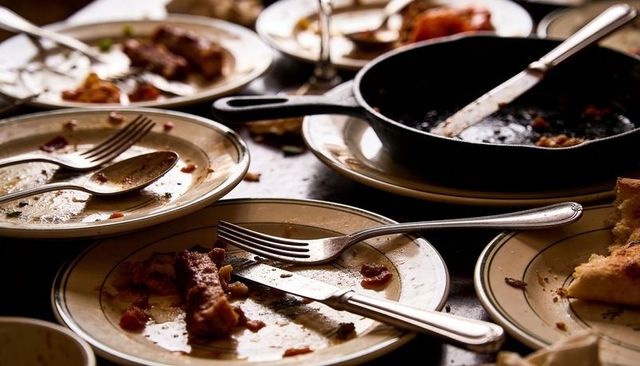 After-meal clutter featuring used plates, utensils and cast-iron skillet on rustic table