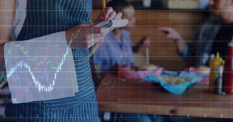 Server writing order with sales chart overlay for restaurant analytics and growth