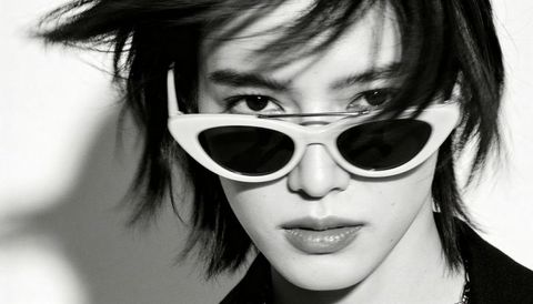 Lowering white cat-eye sunglasses, staring through lenses in striking monochrome fashion portrait