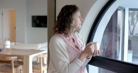 Senior Woman Enjoying Quiet Moment by Arched Window at Home