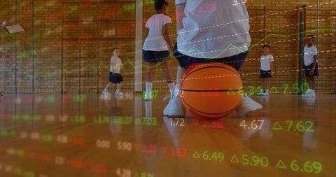 Crouching boy holding basketball in school gym with financial data overlay and training