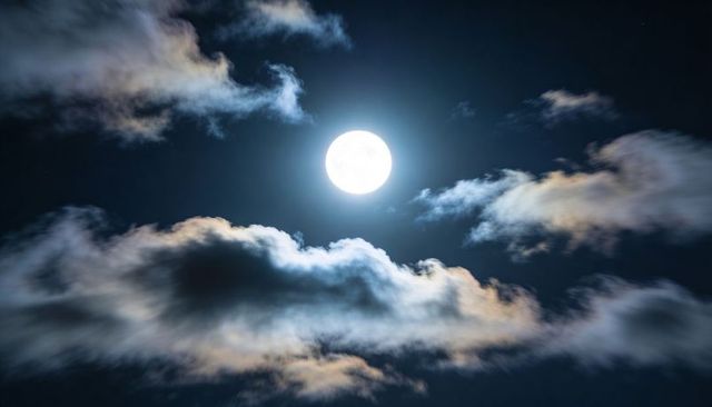 Luminous Full Moon Casting Halo Over Layered Clouds and Deep Night Sky with Soft Lunar Glow