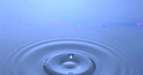 Water Droplet Creating Ripples on Blue Surface