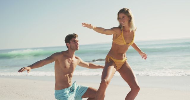 Couple practicing surfing on surfboard at beach wearing swimwear. Perfect for summer vacation themes, lifestyle blogs, fitness and wellness promotions, travel advertisements.