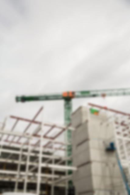 Blurred view of crane and partially constructed building. Suitable for representing construction projects, industrial development, and engineering themes. Ideal for use in presentations, reports, and websites related to construction, architecture, and urban development.
