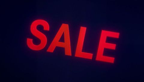 Glowing bold red SALE sign in moody dark storefront featuring neon halo and film grain