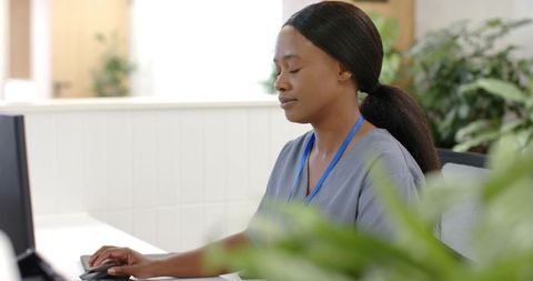 Calm nurse taking brief rest at clinic reception desk with computer mouse nearby