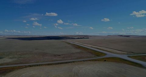 Aerial view of highway intersection through vast farmland under blue sky