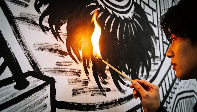 Holding lit match and leaning toward monochrome mural, asian man studying flame