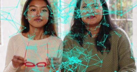 Mother daughter wearing knit sweaters holding red glasses with turquoise network overlay