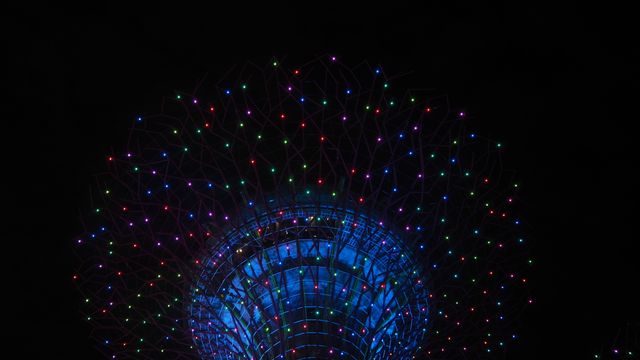 Close-up view of a structure illuminated with vibrant, multicolored LED lights against night sky. Ideal for use in projects related to modern architecture, lighting design, night photography, or visual effects. Suitable for publications on urban technology, night-time art installations, or innovative light displays.