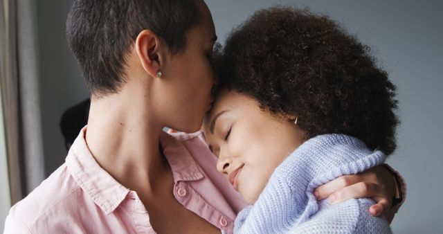 Happy diverse lesbian couple embracing and kissing by window in sunny home - Download Free Stock Photos Pikwizard.com