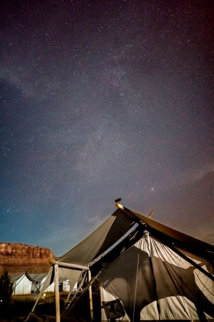 Experience the serene beauty of a starry night in the desert with prominent tents in the foreground. Perfect for promoting outdoor adventure, travel destinations, camping gear, or educational materials on astronomy. Highlights a tranquil, mystical atmosphere ideal for inspiring wanderlust or illustrating remote, natural escape.
