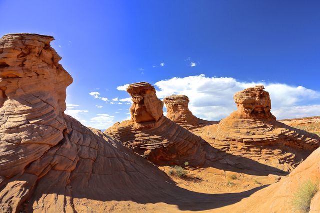 Image captures unique rock formations in a desert area beneath a clear blue sky. Ideal for travel promotional materials, geological studies, nature photography, and outdoor adventure content. Highlights natural beauty and geomorphological features.