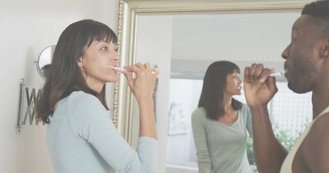 Couple Brushing Teeth Together at Vanity Morning Routine in Bright Bathroom
