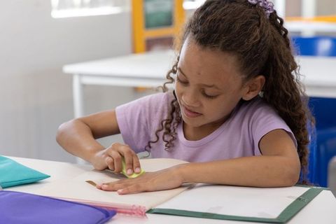 African american girl erasing in notebook at classroom desk learning and focusing