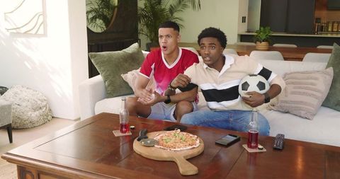 Young Men Enthusiastically Watching Soccer Match on TV