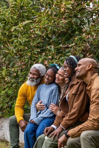 Multigenerational black family sharing warm moments outdoors, smiling and hugging