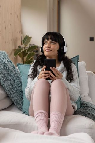 Young Woman Relaxing with Headphones and Smartphone at Home