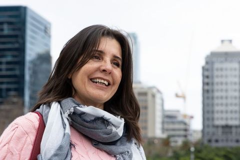 Smiling woman looking upward in downtown plaza wearing gray scarf and pink knit sweater