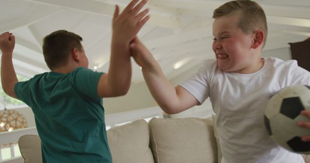 Two Boys Playfully Fighting in Modern Living Room with Soccer Ball - Download Free Stock Images Pikwizard.com