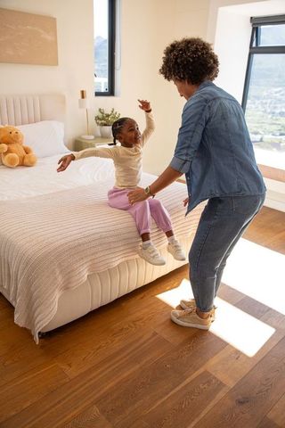 Mother and child reaching for each other in cozy bedroom