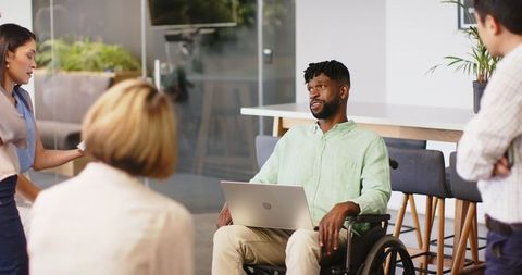 Inclusive office meeting featuring diverse team member with laptop