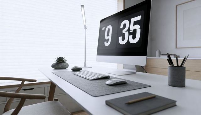 Scandinavian minimalist workspace showing flip-clock monitor, keyboard, mouse, daylight