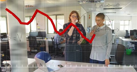 Female architects analyzing blueprint with graphical data