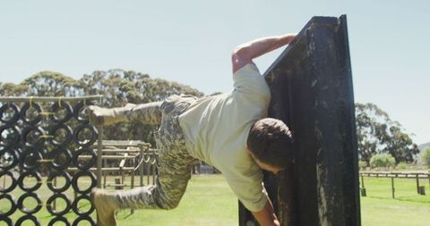 Soldier Climbing Obstacle Course Fence in Training Session