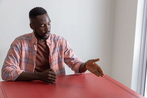 Mid Adult Man Gesturing Thoughtfully over Red Table