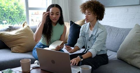 Two African American Women Collaborating on Laptop in Cozy Living Room for Remote Work