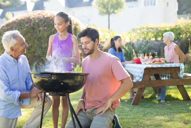 Family spending quality time together in a park, enjoying a barbecue. Ideal for promoting family activities, outdoor events, summer gatherings, and leisure time. Perfect for advertisements, brochures, and websites focused on family bonding, outdoor fun, and community events.