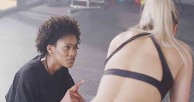 Image of diverse female trainer and woman talking after working out at a gym. Exercise, fitness and healthy lifestyle.
