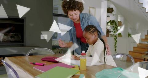 Caregiver guiding child through homework at home dining table, tutoring and focused learning